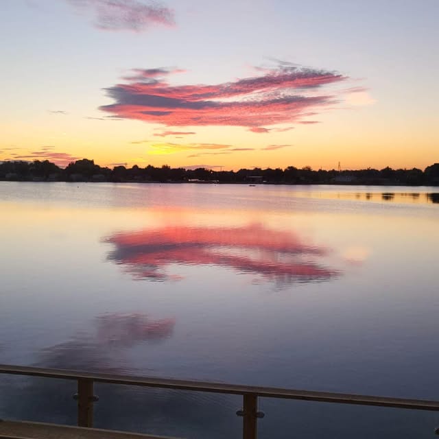 Pink clouds mirrored in the lake at sunset